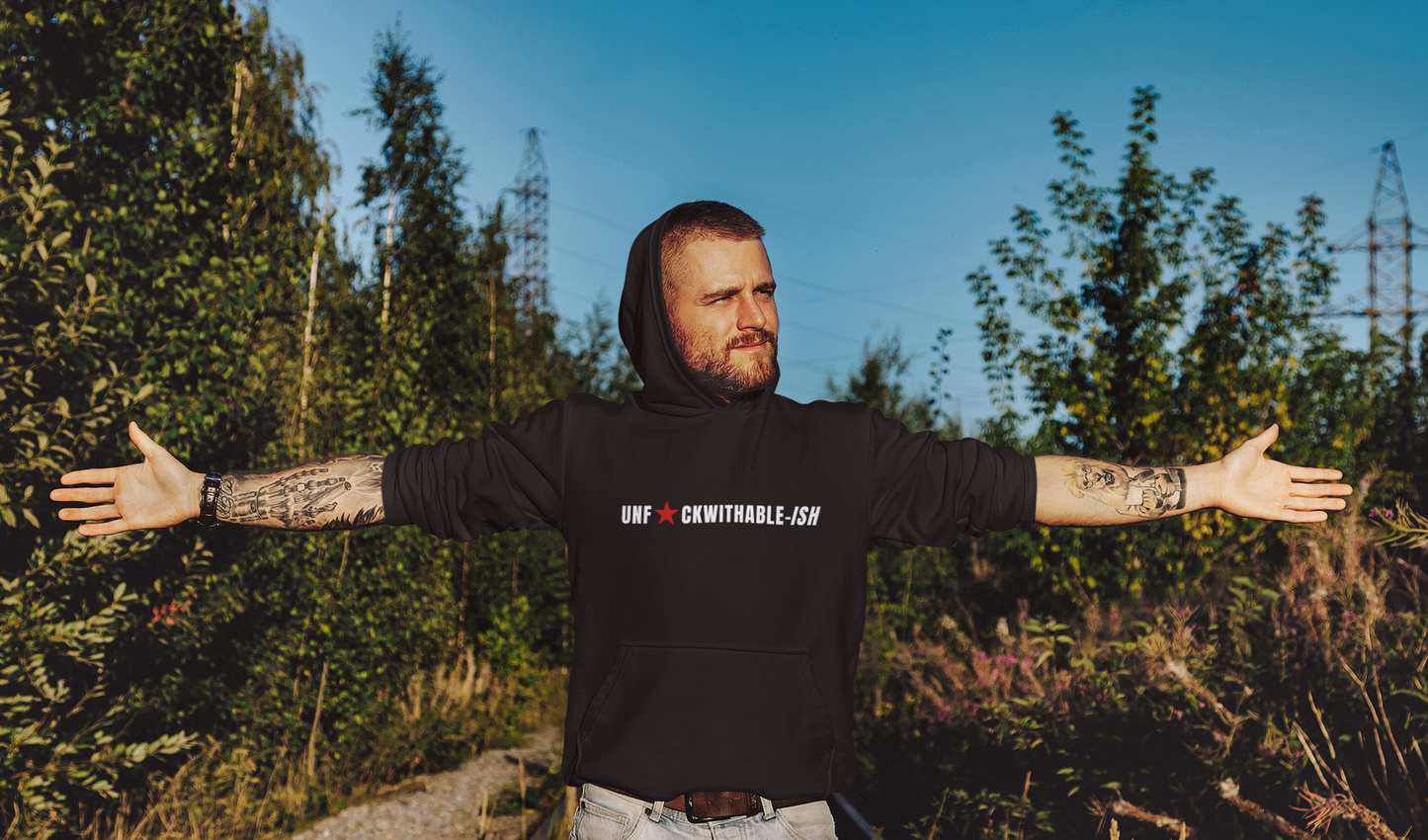 Man wearing a black hoodie with text, standing outdoors with arms outstretched.